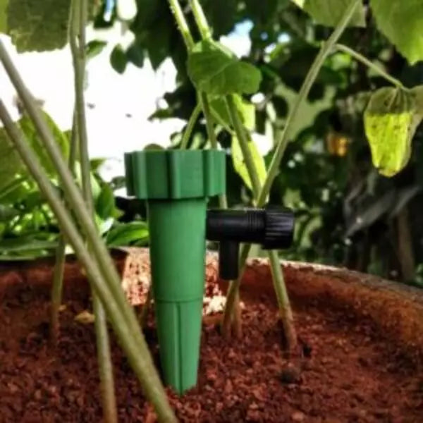 This is an image of Watering Spikes for Plants placed in mud with greenery in background.