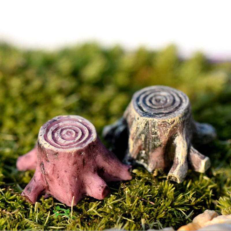 Two miniature tree trunks kept on a bed of grass.