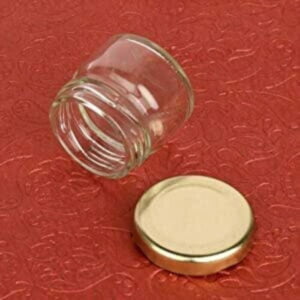 Small jars with metallic caps kept against a red background