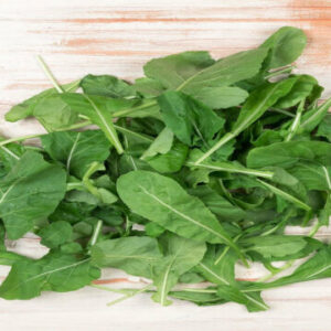 Several bright green spinach leaves tied together in a bunch on a black mat.