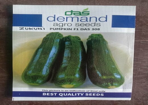 This is an image of a packet of Demand Agro Pumpkin F1 Das (Zucchini) Seeds kept against brown color background.