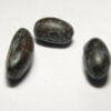Few large oblong jet black bean seeds kept against a white background