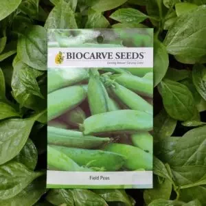 This is an image of a packet of Biocarve Field Peas Seeds kept against a green leafy background.