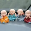 A Miniature Monks Assorted with cute expressions kept on a car dashboard with glass window as a background.