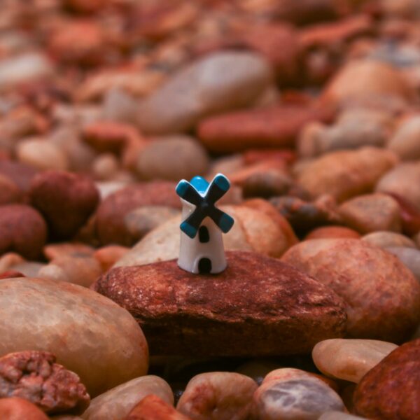 Small and cute Miniature Windmill Assorted on a brown stone with several stones in the background.