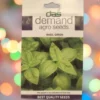 This is an image of a packet of Demand Agro Basil Green Seeds kept against a colorful background.