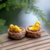 A cute 2 Miniature Bird Nests on a wooden bench with a tree stem in the background.