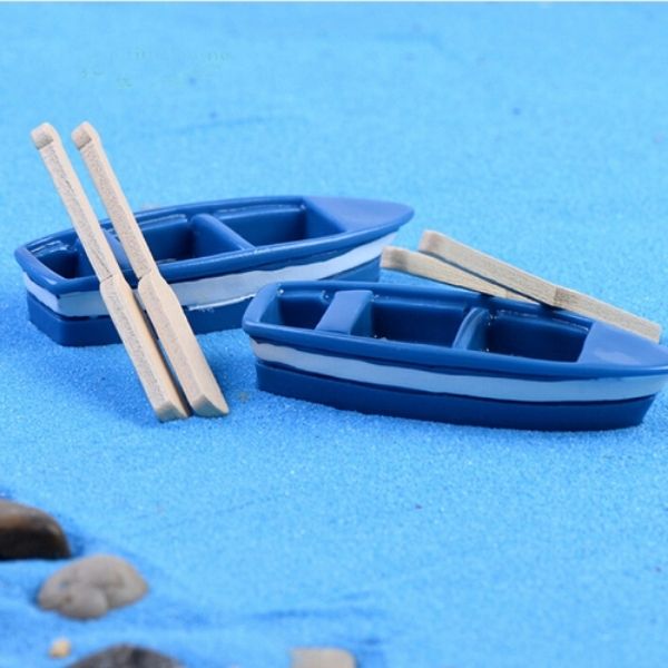 A beautiful and cute two Miniature boats with Oars on a blue surface.