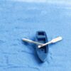 A beautiful and cute Miniature boat with Oars on a blue surface.