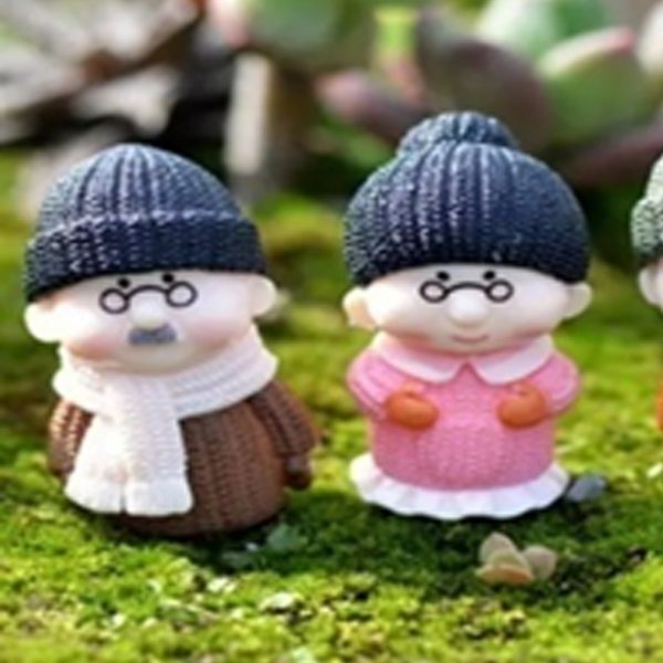 A cute small Miniature Old Couple Grandparents on lawn grass.