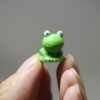 A hand holding cute Miniature Toy Frog.