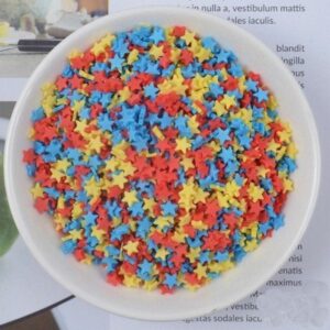 Several colorful Miniature Polymer Clay Stars in a ceramic bowl.