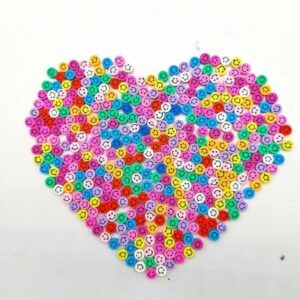 Several varieties of Miniature Polymer Clay Smilies are arranged in a heart shape.