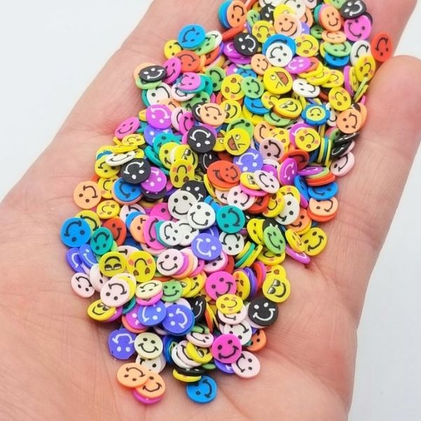 Several variety of Miniature Polymer Clay Smiles on a hand.