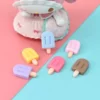 A set of colorful Miniature Dollhouse Ice Cream on a blue and pink paper with doll in a background.