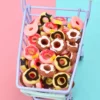 A several colorful Miniature Dollhouse Doughnuts on a cart kept on blue and pink color floor.