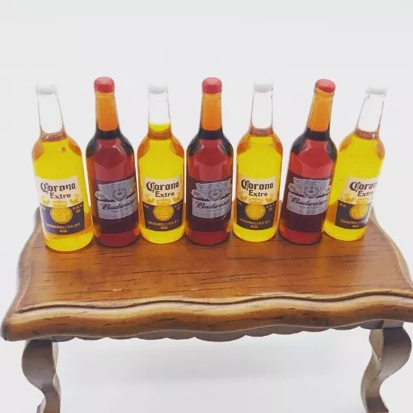 A Miniature Beer Bottles kept on a brown table with white as a back ground.