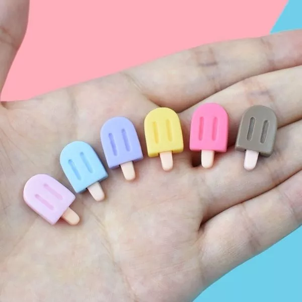 A set of colorful Miniature Dollhouse Ice Cream kept in a hand with blue and pink background.