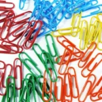 This is an image of multiple Multi colored paper clips against white color background.