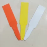 This is an image of three Arrow-Shaped Plant Tags of orange, yellow and white color kept against white color background.